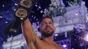 Veteran fighter raising a championship belt at an outdoor night event, symbolizing Justin Gaethje's late-career title win